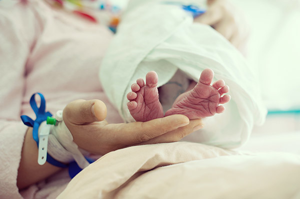 Newborn baby in hospital with id ribbon on his hand